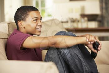 Teenage Boy Sitting On Sofa At Home Watching Television