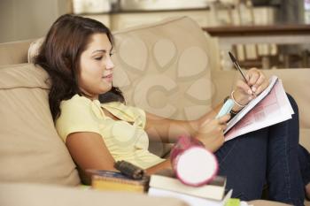 Teenage Girl  Sitting On Sofa At Home Doing Homework