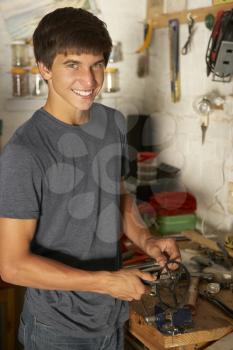 Teenage Boy Using Workbench In Garage