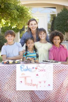 Group Of Children Holding Bake Sale With Mother