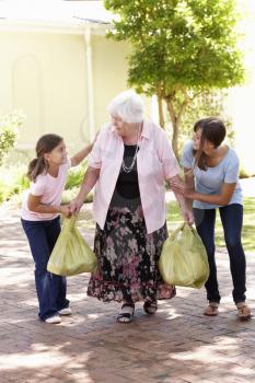 Grandchildren Helping Grandmother To Carry Shopping