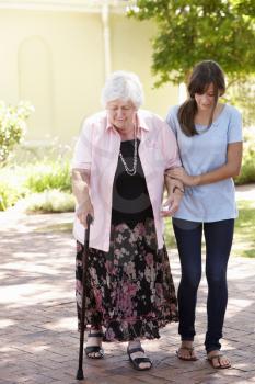 Teenage Granddaughter Helping Grandmother Out On Walk