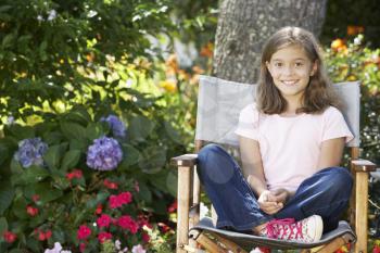 Young Girl Sitting Outdoors In Garden Chair