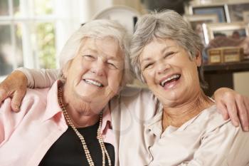 Portrait Of Two Retired Senior Female Friends Sitting On Sofa