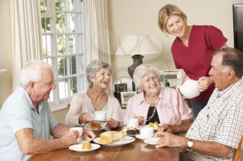 Group Of Senior Couples Enjoying Afternoon Tea Together At Home With Home Help