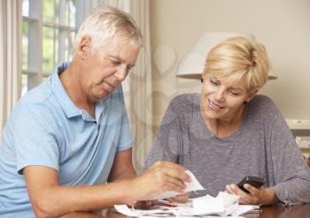 Mature Couple Checking Finances And Going Through Bills Together