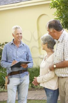 Repairman Giving Senior Couple Estimate For Roof Repair