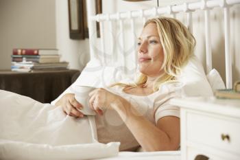 Woman Relaxing In Bed With Hot Drink