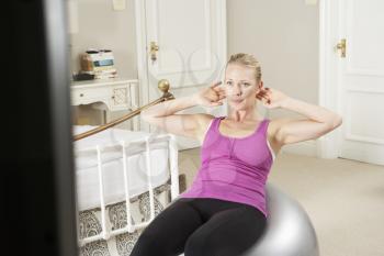 Woman Exercising Whilst Watching Fitness DVD On Television