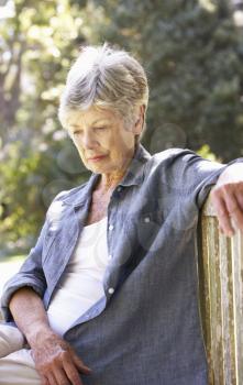 Unhappy Senior Woman Sitting On Park Bench