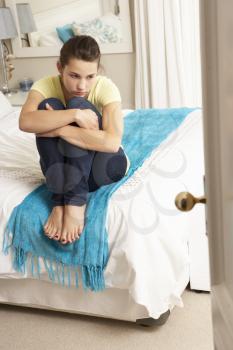 Depressed Teenage Girl Sitting On Bed