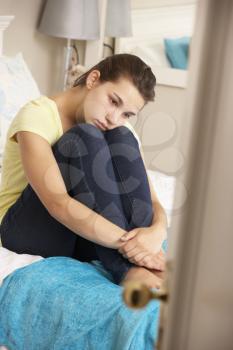 Depressed Teenage Girl Sitting On Bed