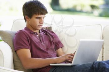 Teenage Boy Relaxing On Sofa At Home Using Laptop