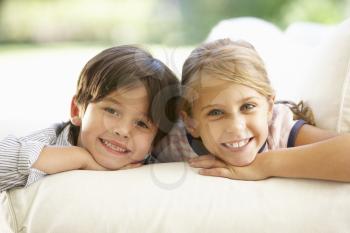 Two Children Relaxing On Sofa At Home