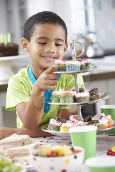 Young Boy Standing By Table Laid With Birthday Party Food