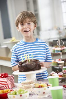 Young Boy Standing By Table Laid With Birthday Party Food