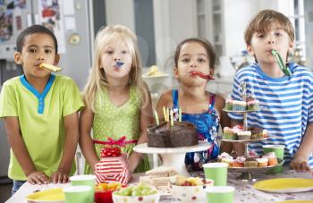 Group Of Children Standing By Table Laid With Birthday Party Food