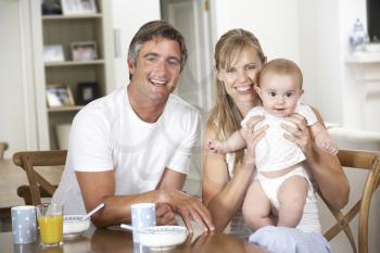 Family With Baby Having Breakfast In Kitchen Together