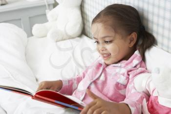 Young Girl Wearing Pajamas In Bed Reading Book