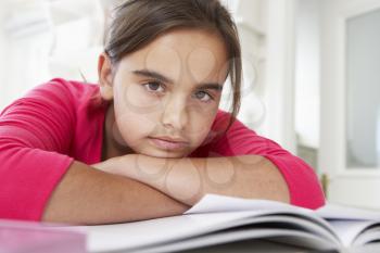 Bored Young Girl Doing Homework At Desk In Bedroom