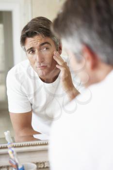 Man Looking At Reflection In Bathroom Mirror