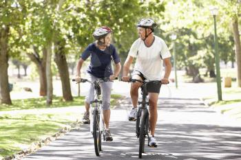Mature Couple Cycling Through Park