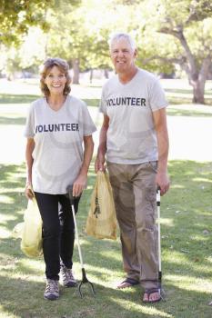 Senior Couple Working As Part Of Volunteer Group Clearing Litter In Park