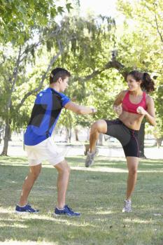 Young Woman Working With Personal Trainer In Park