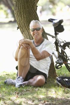 Mature Man Resting On Cycle Ride Through Park