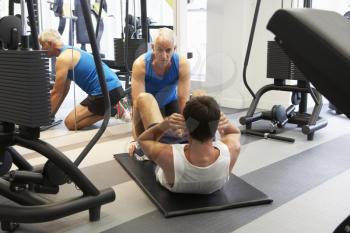 Man Working With Personal Trainer In Gym