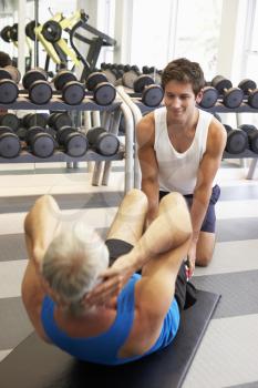 Middle Aged Man Working With Personal Trainer In Gym