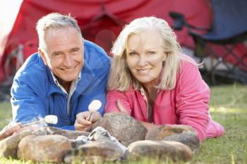 Senior Couple Toasting Marshmallows Over Fire Camping Holiday