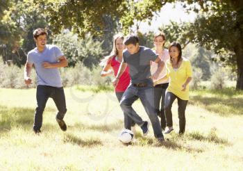 Group Of Young Friends Playing Soccer In Countryside