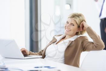 Portrait Of Female Executive Using Laptop Relaxing In Office