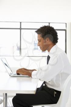 Businessman Sitting At Desk In Office Using Laptop