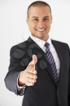 Studio Portrait Of Businessman Reaching Out To Shake Hands