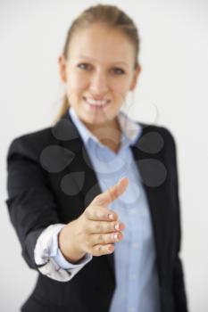 Studio Portrait Of Businesswoman Reaching Out To Shake Hands