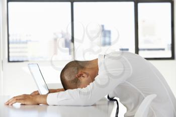 Frustrated Businessman Sitting At Desk In Office Using Laptop