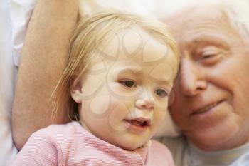 Grandfather Cuddling Granddaughter In Bed