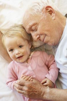 Grandfather Cuddling Granddaughter In Bed