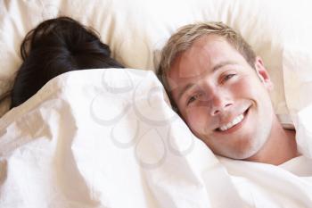 Couple Relaxing In Bed Hiding Under Bedclothes