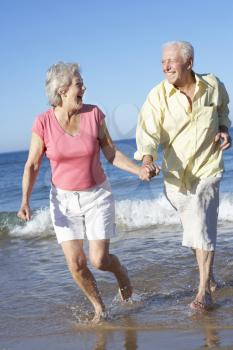 Senior Couple Running Along Beach Together