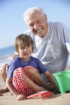 Grandfather And Grandson Building Sandcastle On Beach