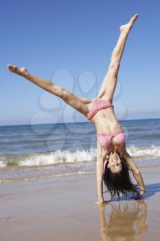 Woman Turning Cartwheel On Beach Holiday