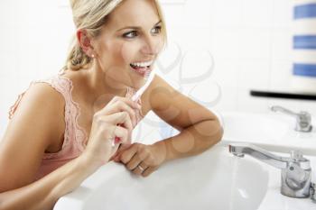 Woman In Bathroom Brushing Teeth