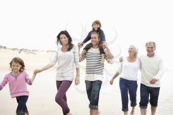 Multi Generation Family Walking Along Beach Together