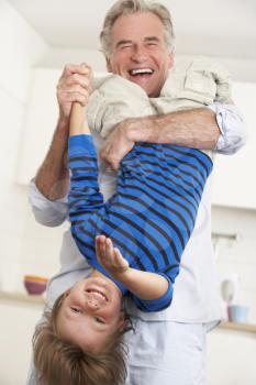 Grandfather Holding Grandson Upside Down At Home