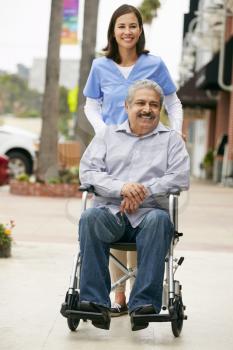 Carer Pushing Disabled Senior Man In Wheelchair
