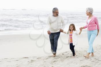 Grandparents Walking Along Beach With Granddaughter