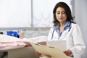 Female Doctor In Surgery Reading Patient Notes